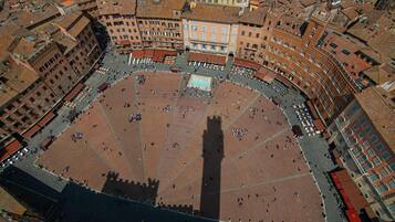 An aerial view of a historic square with a central open space surrounded by buildings with red-tiled roofs.