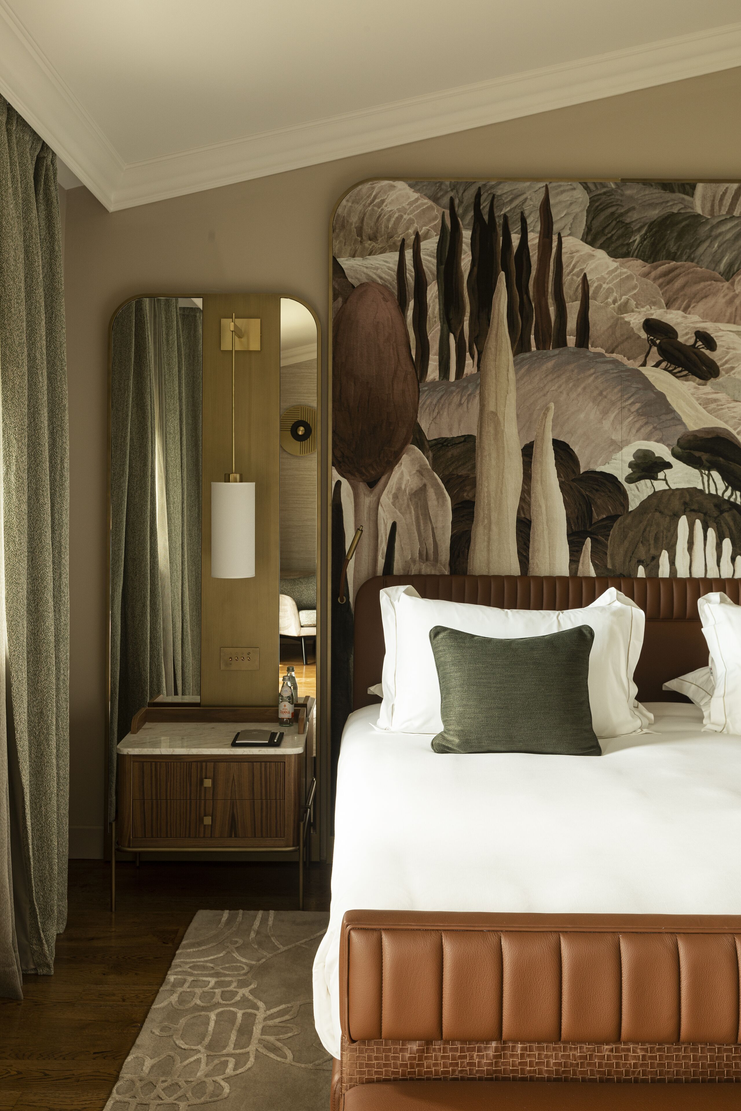 Ein Hotelzimmer mit einem großen Bett, einem Spiegel, einem Schminktisch und einem Wandgemälde.