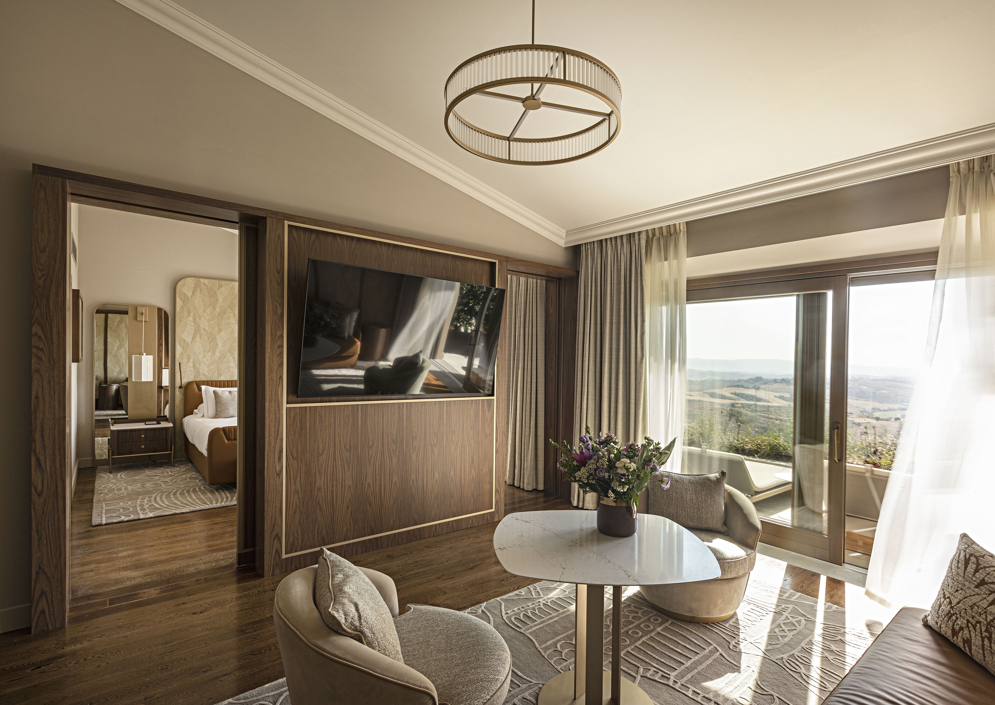 Une chambre d’hôtel spacieuse avec un grand lit, un coin salon avec une table, une télévision et un balcon offrant une vue agréable.