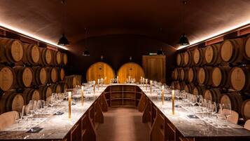 A wine tasting room with a long table set for guests, surrounded by wooden wine barrels.