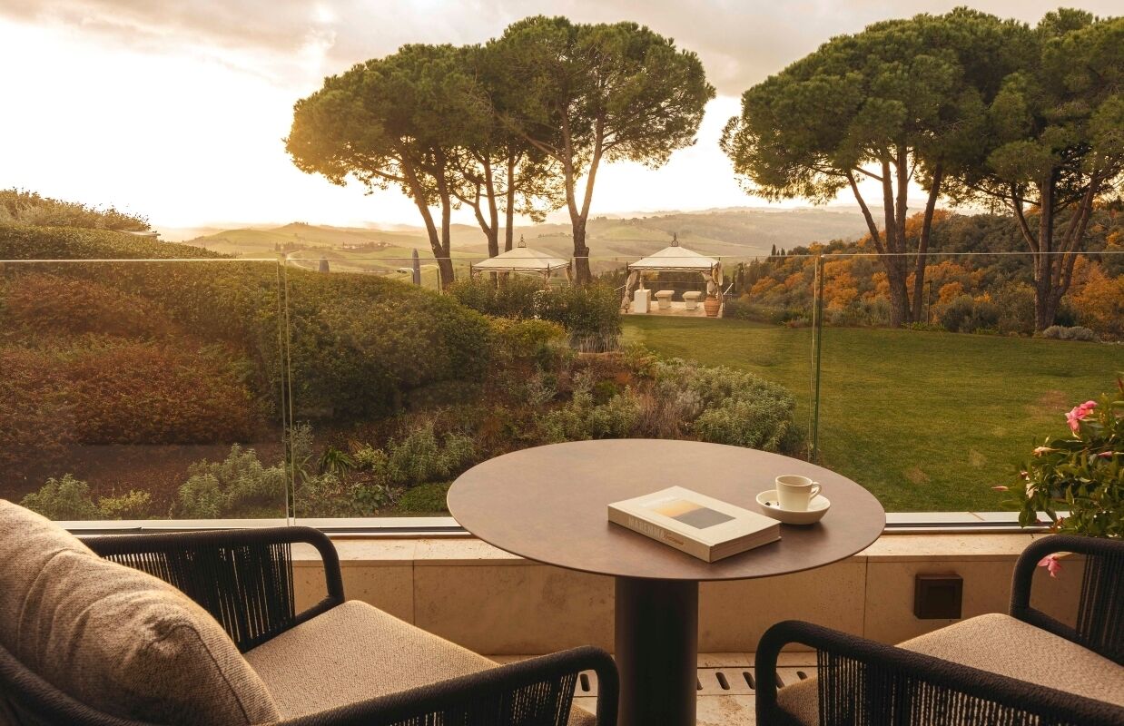 Una terrazza con un tavolo rotondo, due sedie e un libro.