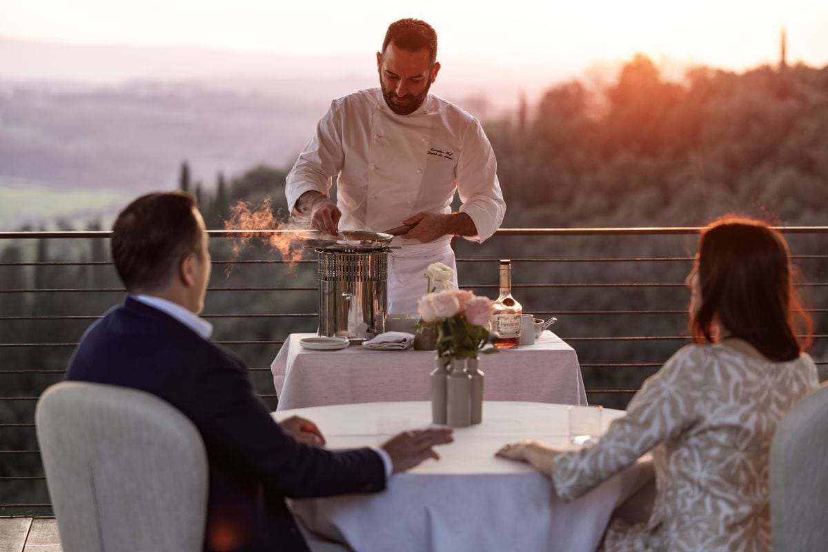 A chef cooking outdoors with a table set for two people.