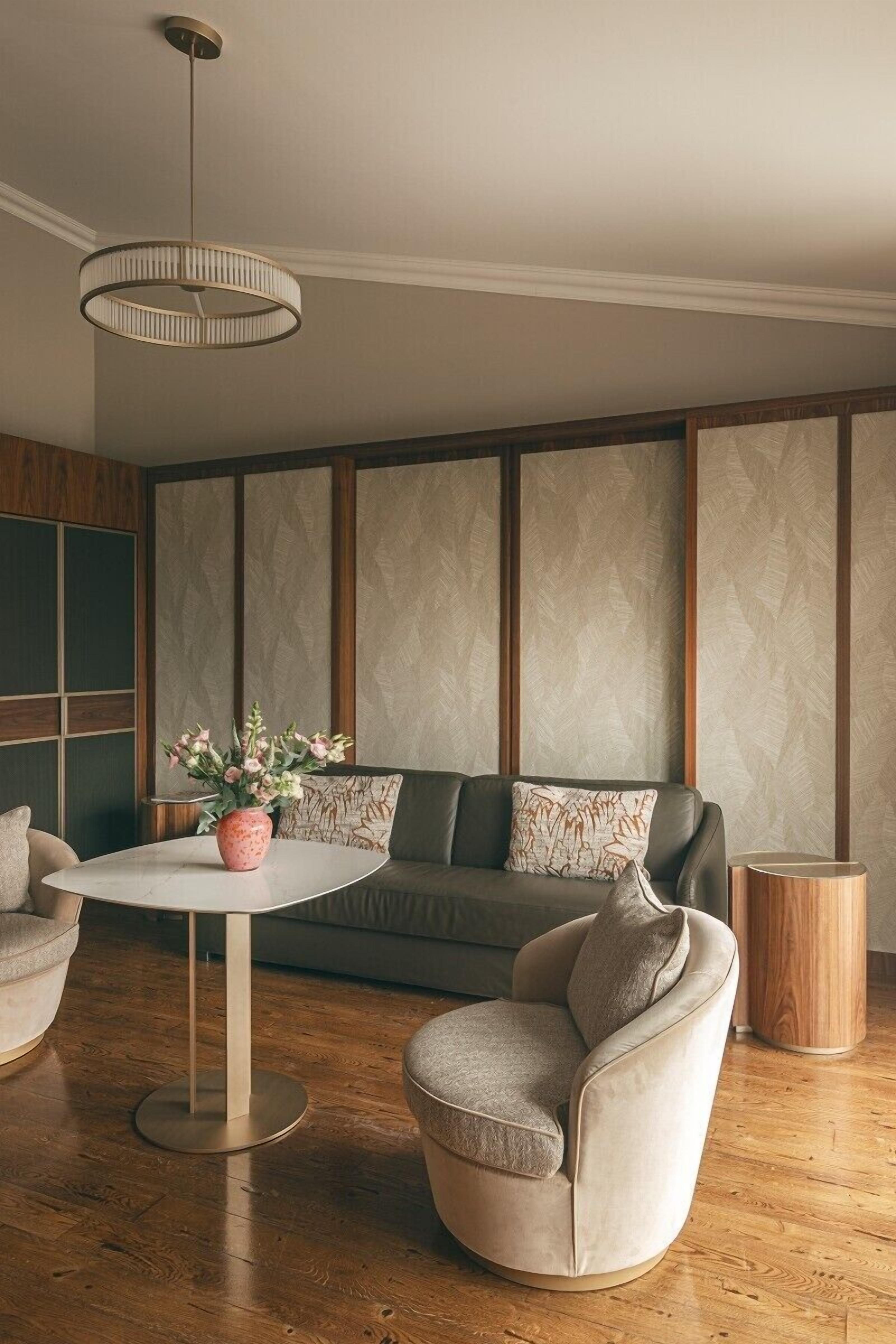 Ein modernes Wohnzimmer mit einem runden Tisch, zwei Sesseln, einer Couch und einer Zierdevasė.
