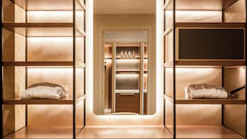 A modern, well-lit walk-in closet with wooden shelving and a central mirror.