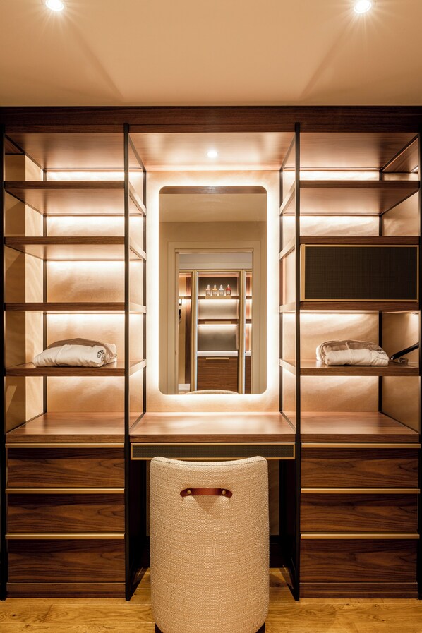 A modern, well-lit walk-in closet with wooden shelving and a central mirror. - Castelfalfi (Montaione)