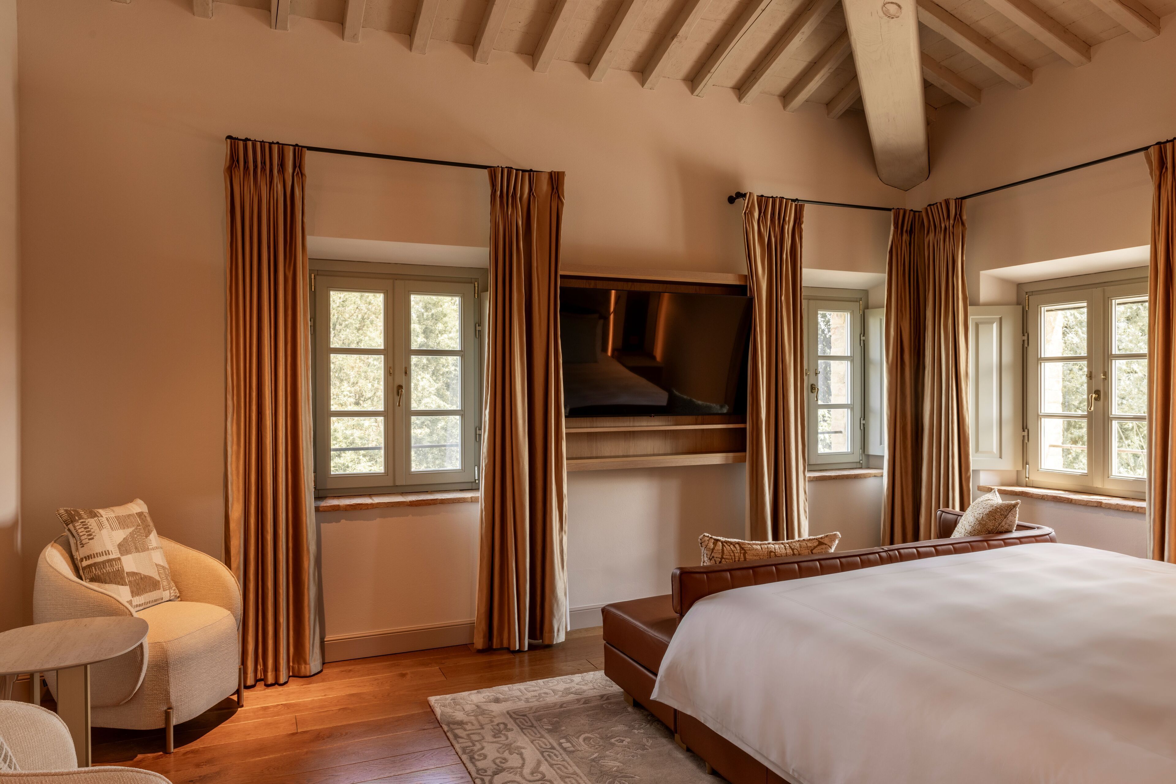 Un dormitorio con una cama grande, un televisor montado en la pared y un sofá.