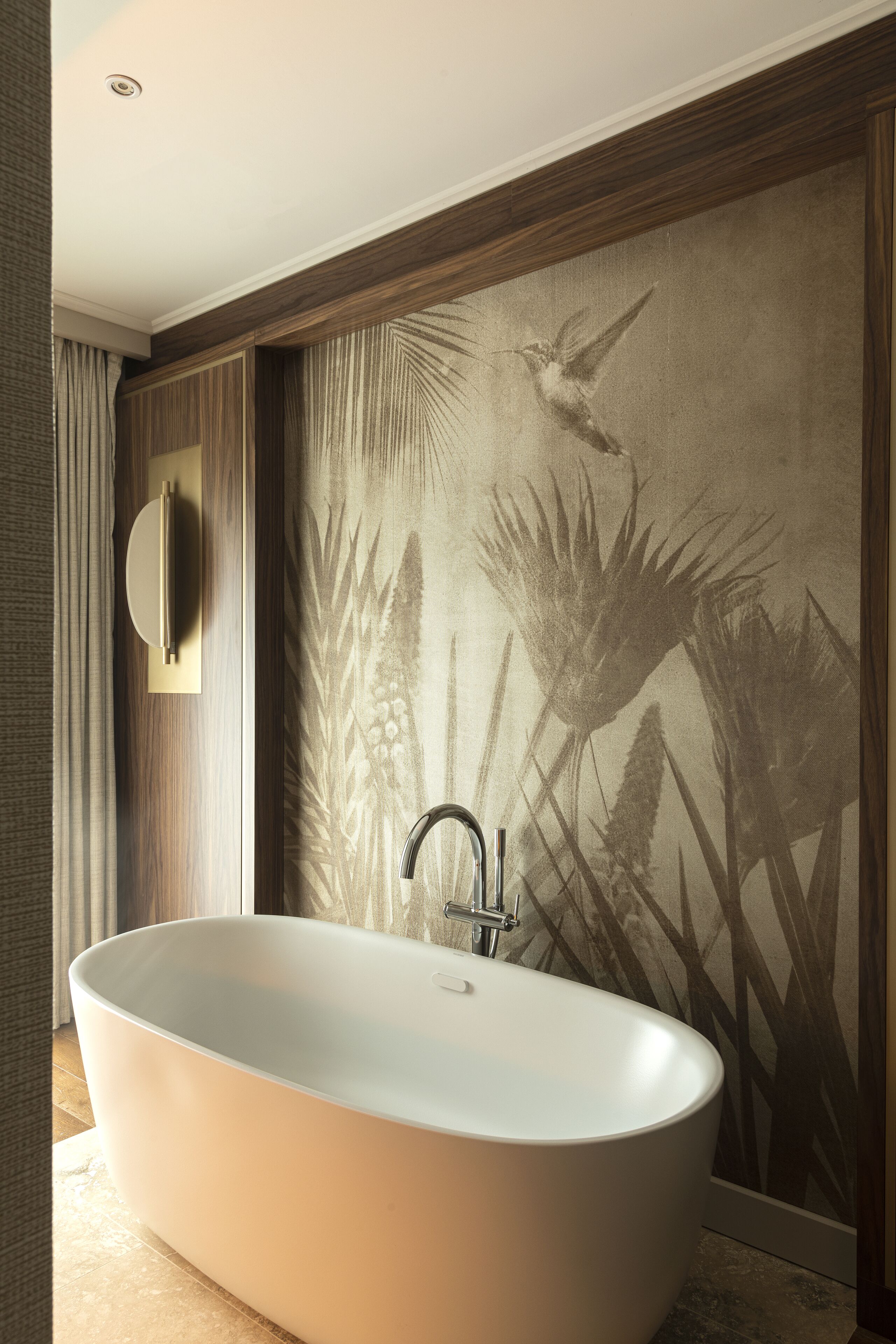 Un baño moderno con una bañera independiente, un espejo montado en la pared y un panel decorativo.