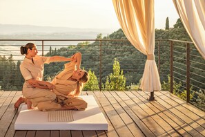 Une personne effectuant une posture de yoga sur une terrasse en bois, avec une vue sur un paysage.
