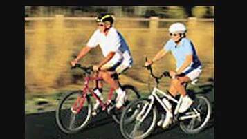 Duas pessoas andando de bicicleta numa estrada.