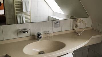 Un baño moderno con un lavamanos grande, un espejo, un perchero para toallas y una ducha.