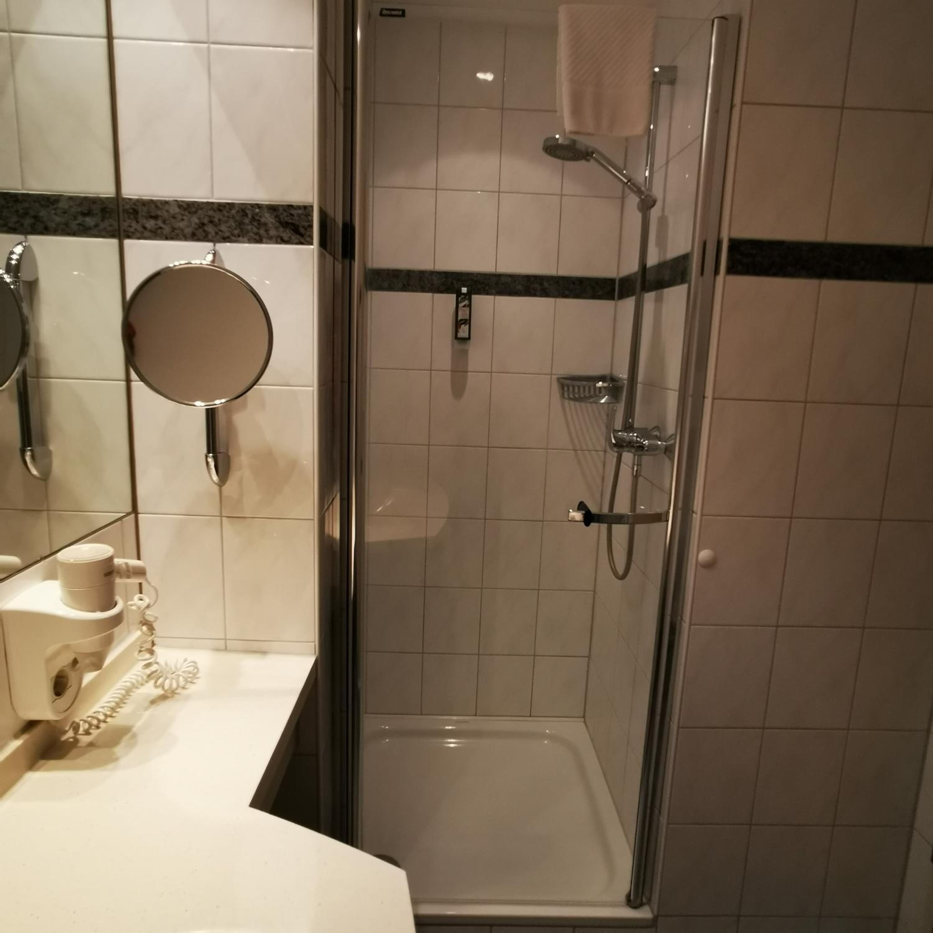 Una ducha con puerta de vidrio y dos duchas de mano.