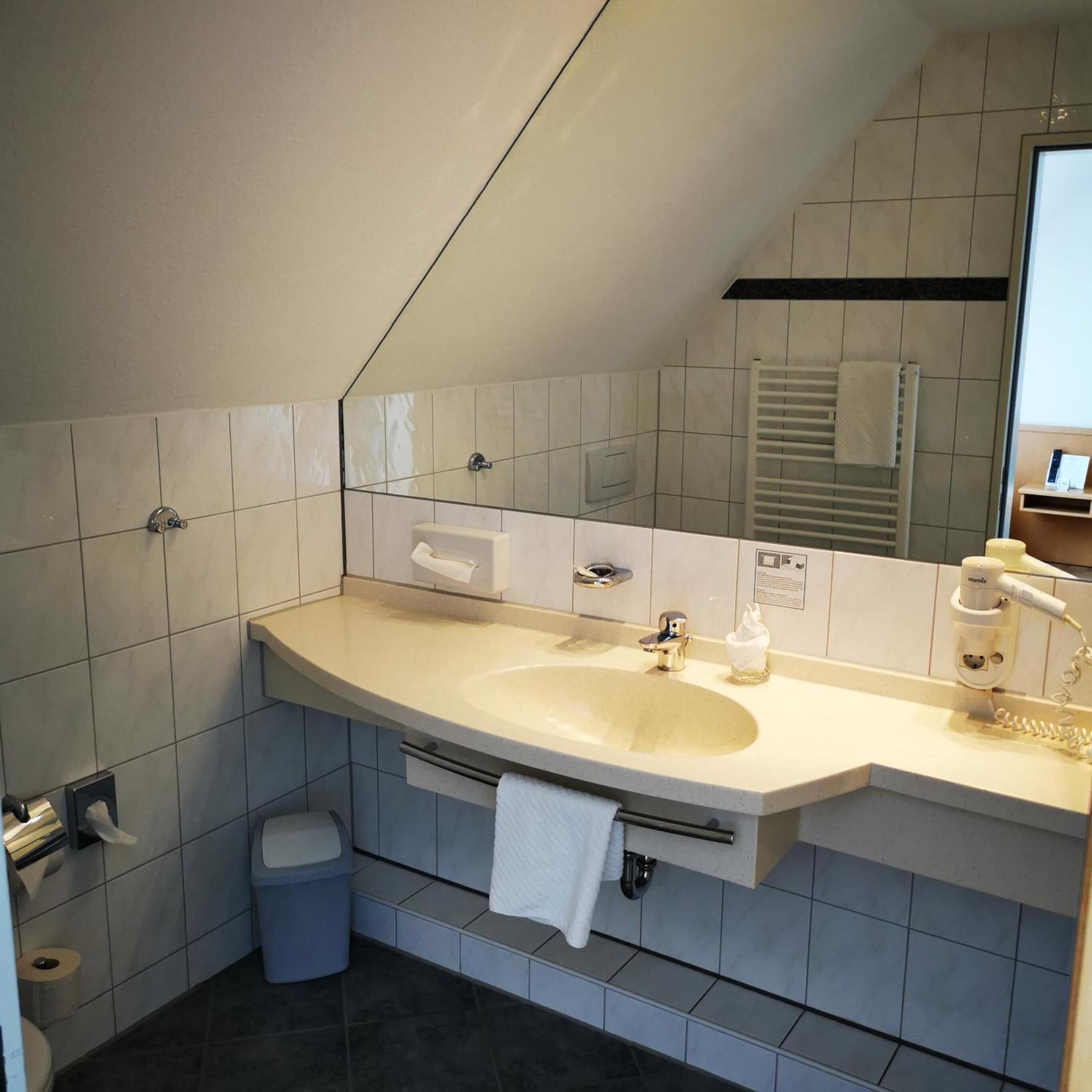 Un baño moderno con un lavabo grande, un perchero para toallas y un espejo.