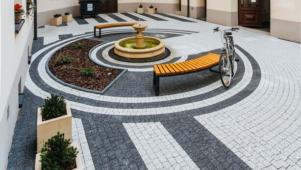 A courtyard with a fountain, benches, and a bicycle. - EchoDom 8 Apartments Zygmunta Augusta (Kraków)
