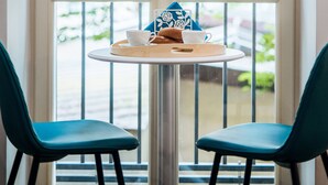 A room with a large window, a round table with a tray, two chairs, and a decorative item on the window sill. - EchoDom 8 Apartments Zygmunta Augusta (Kraków)