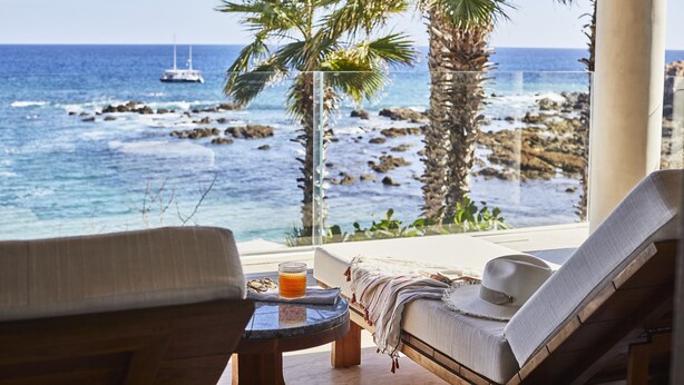 A room with a view of the ocean, a bed, a chair, and a small table with a drink. - Chileno Bay Resort & Residences, Auberge Collection (Cabo San Lucas)