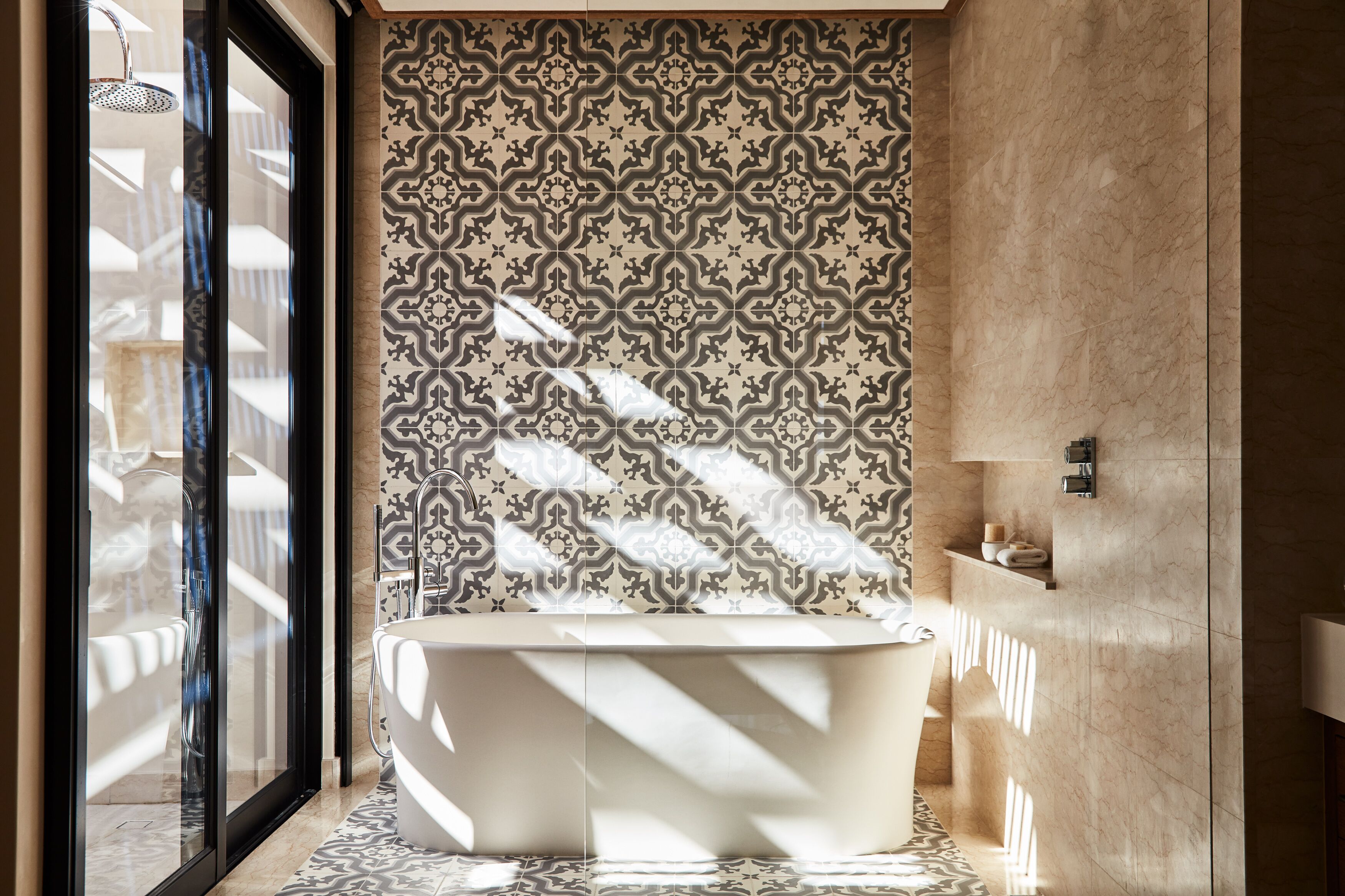 Une salle de bain moderne avec une baignoire sur pieds, des carreaux muraux à motifs et un sol en marbre.