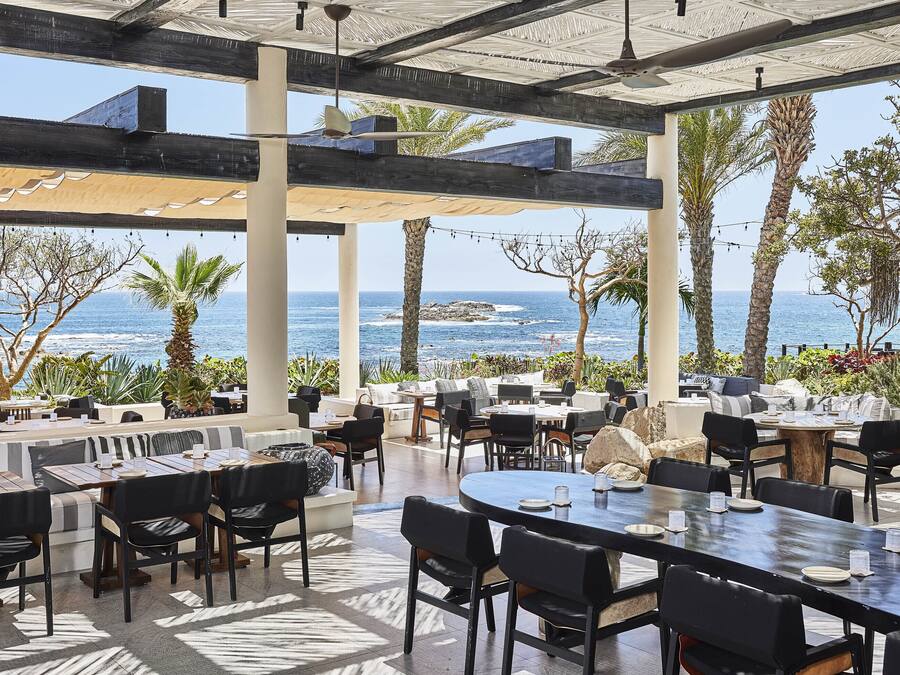 An outdoor dining area with tables and chairs, overlooking the ocean.