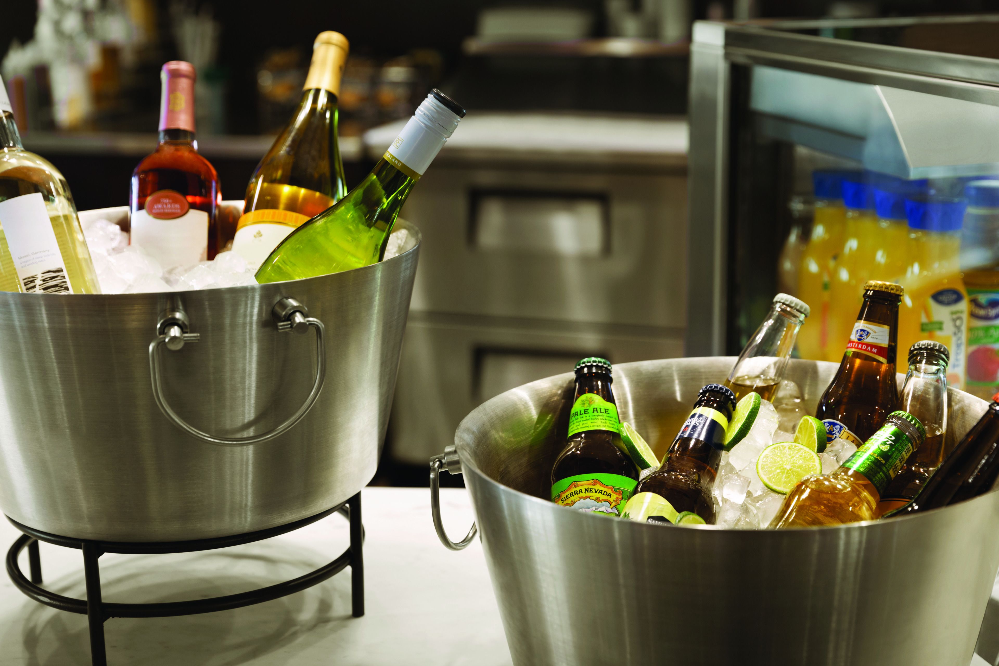 Two metal buckets filled with bottles of beverages, including wine and beer, placed on a countertop.