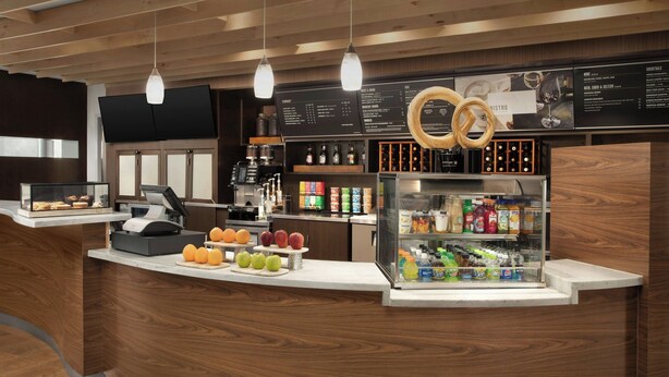 Un espace bar moderne agrémenté d’éléments en bois, avec une machine à café et un présentoir de fruits.