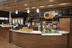 Een moderne bar met houten details, een koffieapparaat en een fruitpresentatie.