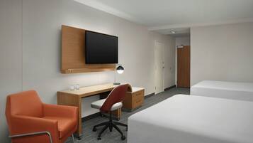 A hotel room with a bed, a desk, a chair, a television, and a wardrobe.