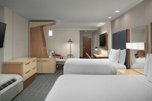 Een moderne hotelkamer met twee bedden, een bureau, een stoel, een kledingkast en een grote spiegel.