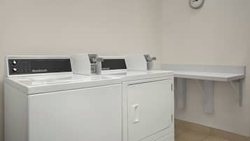 A laundry room with two white front-loading washers and a white sink.
