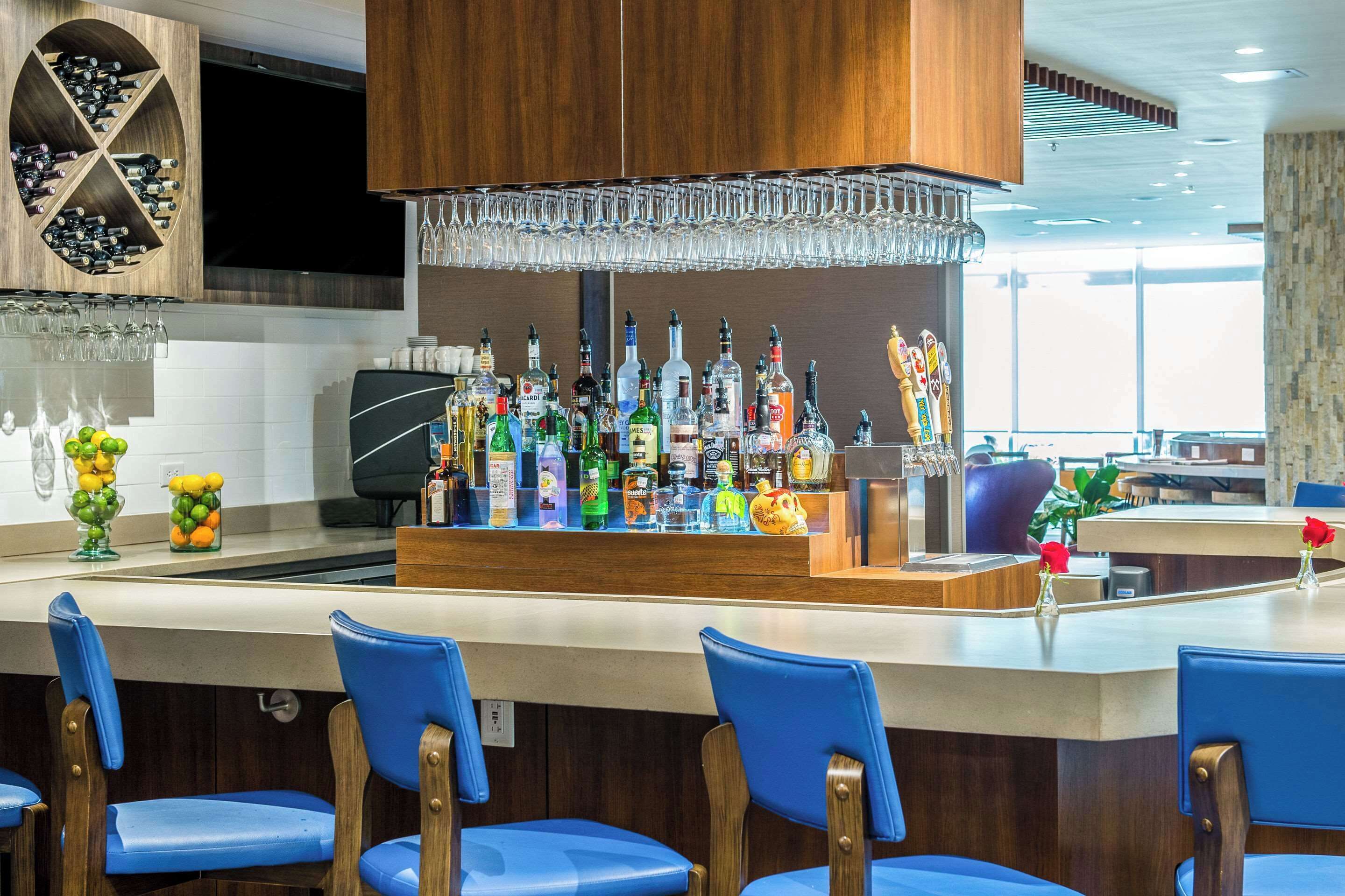 A bar area with a variety of liquor bottles, a wine rack, and blue bar stools.