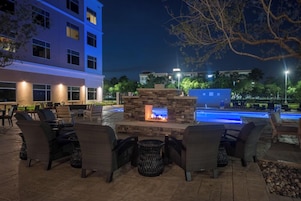 An outdoor seating area with wicker chairs and a stone fire pit.