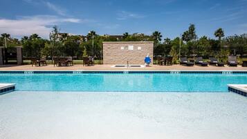 Una piscina con muro de piedra y sillas de descanso.