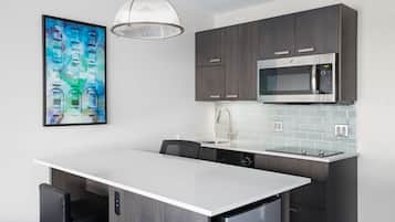 A modern kitchen with dark wood cabinets, a stainless steel microwave, and a white island with seating.