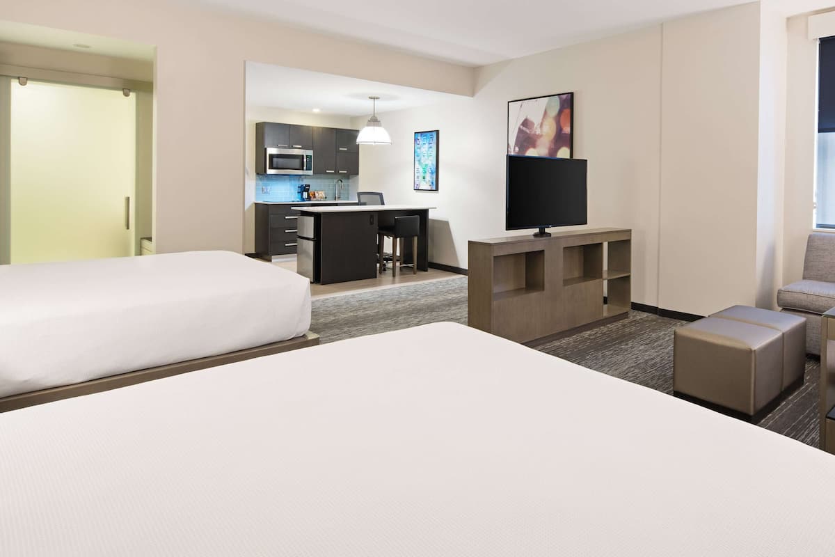 Une chambre d’hôtel avec deux lits, une télévision, un bureau et une kitchenette.