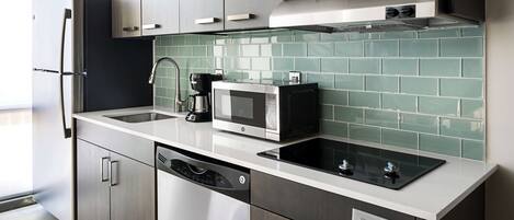 Una cocina moderna con electrodomésticos de acero inoxidable, lavavajillas y un salpicadero de azulejos.