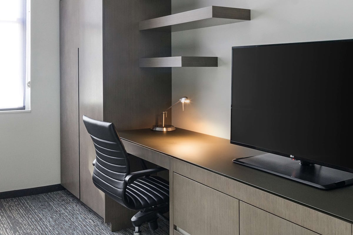 Un bureau moderne doté d’un écran plat, d’une lampe de bureau et d’un fauteuil de bureau noir.