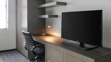 Un bureau moderne doté d’un écran plat, d’une lampe de bureau et d’un fauteuil de bureau noir.