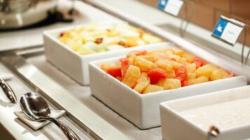 A buffet with various fruit options in white containers, a spoon, and a small sign.
