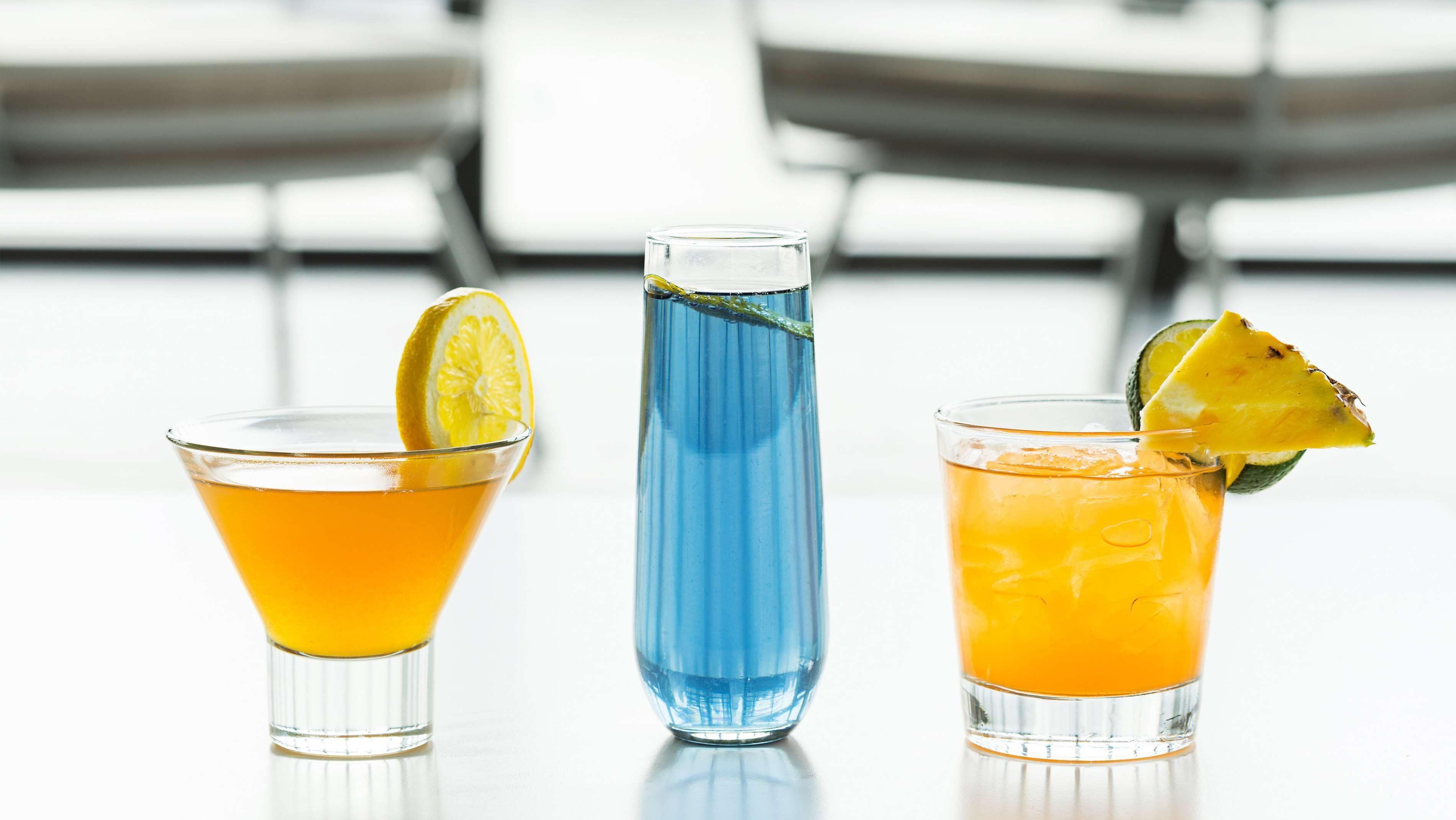 Tres bebidas diferentes en vasos, cada una decorada con una rodaja de fruta.