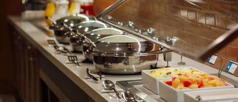 A buffet line with various food containers and utensils.