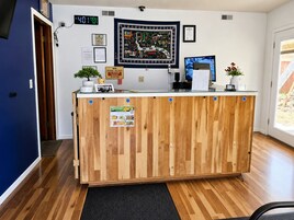 A reception desk with a clock, framed artwork, and a plant.