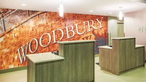 Un área de recepción con un gran letrero de 'WOODBURY' en la pared, una escalera y dos mostradores de recepción.