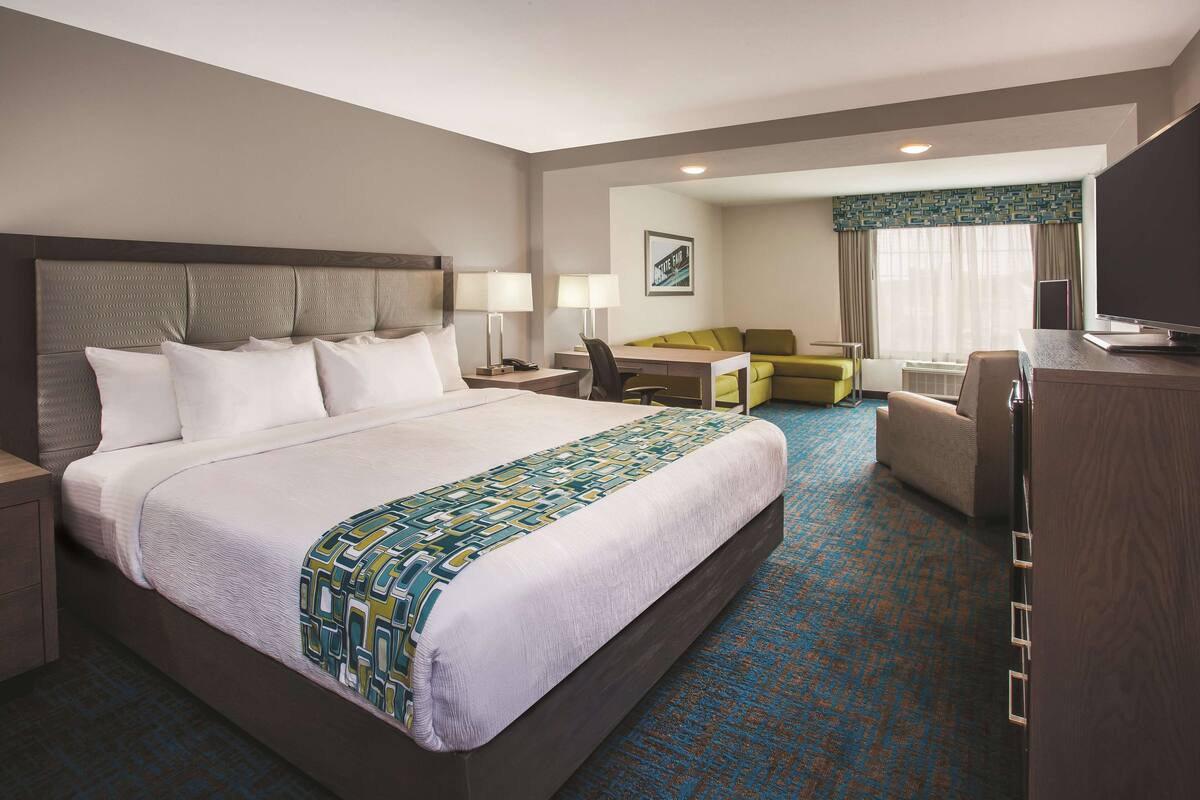 A hotel room with a large bed, a desk, a chair, and a television.