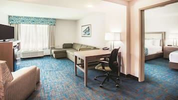 A hotel room with a bed, a desk, a chair, a sofa, a TV, and a large mirror.