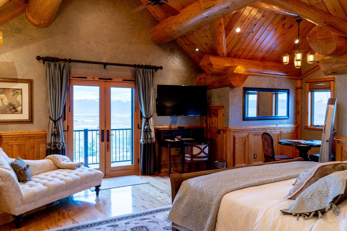 A cozy room with a bed, a sofa, a TV, and a balcony with a view.