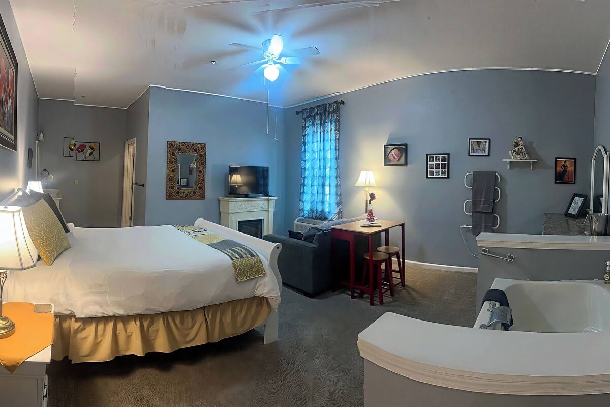 Une chambre d’hôtel comprenant un lit, un bureau, une chaise, une coiffeuse avec un miroir et une baignoire.
