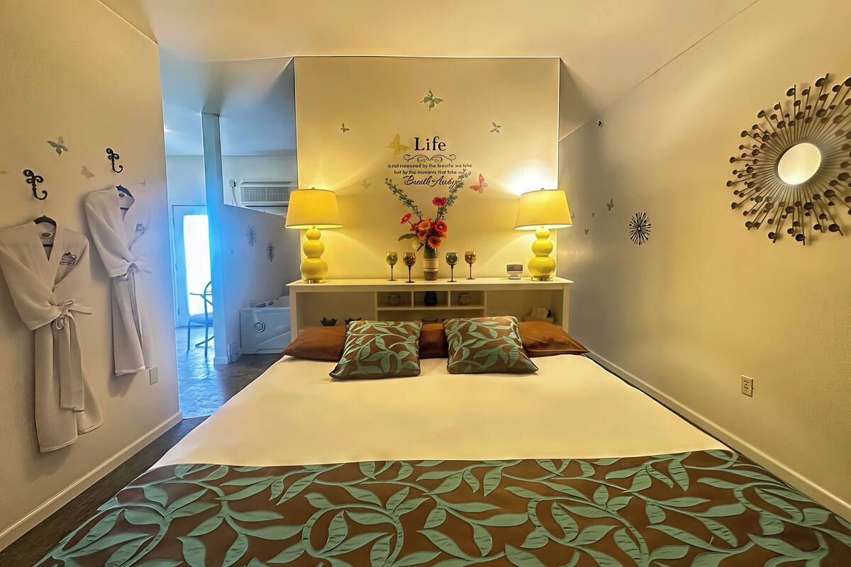Une chambre d’hôtel avec un lit, deux lampes de chevet, une horloge murale et un miroir décoratif.