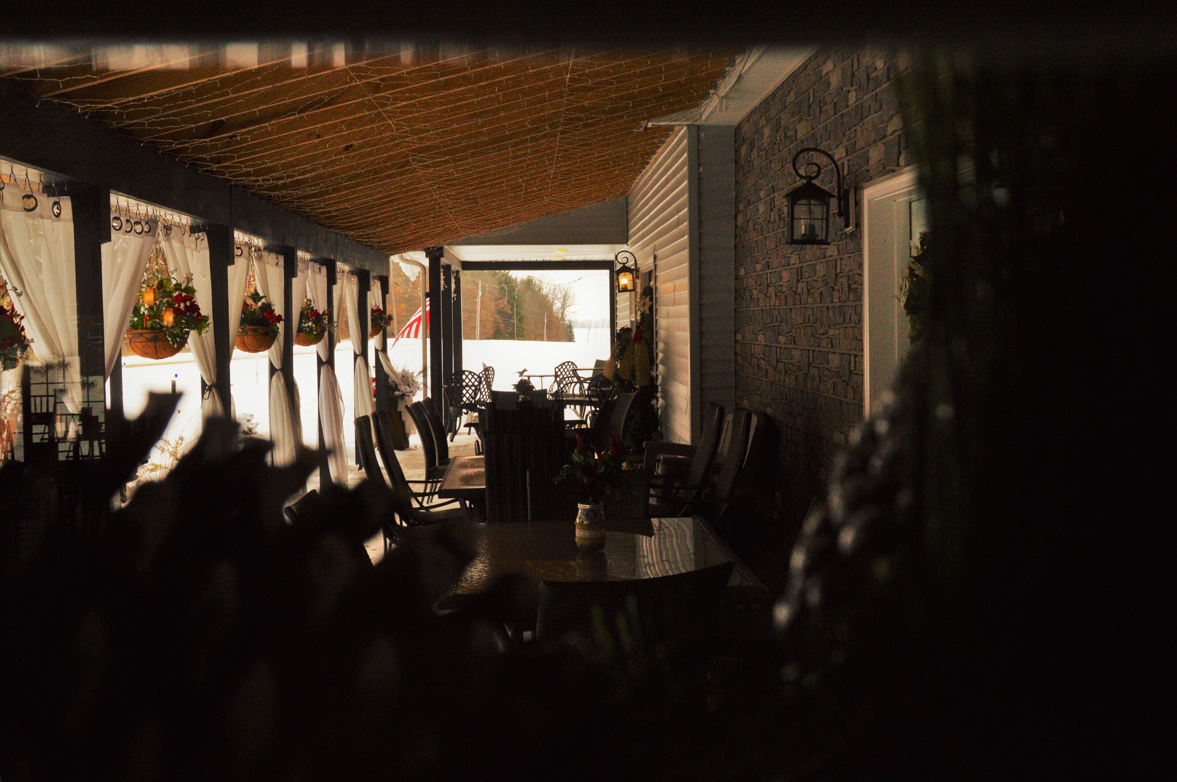 An indoor dining area with hanging flower baskets, a brick wall, and a view through a window.