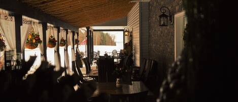 An indoor dining area with hanging flower baskets, a brick wall, and a view through a window.
