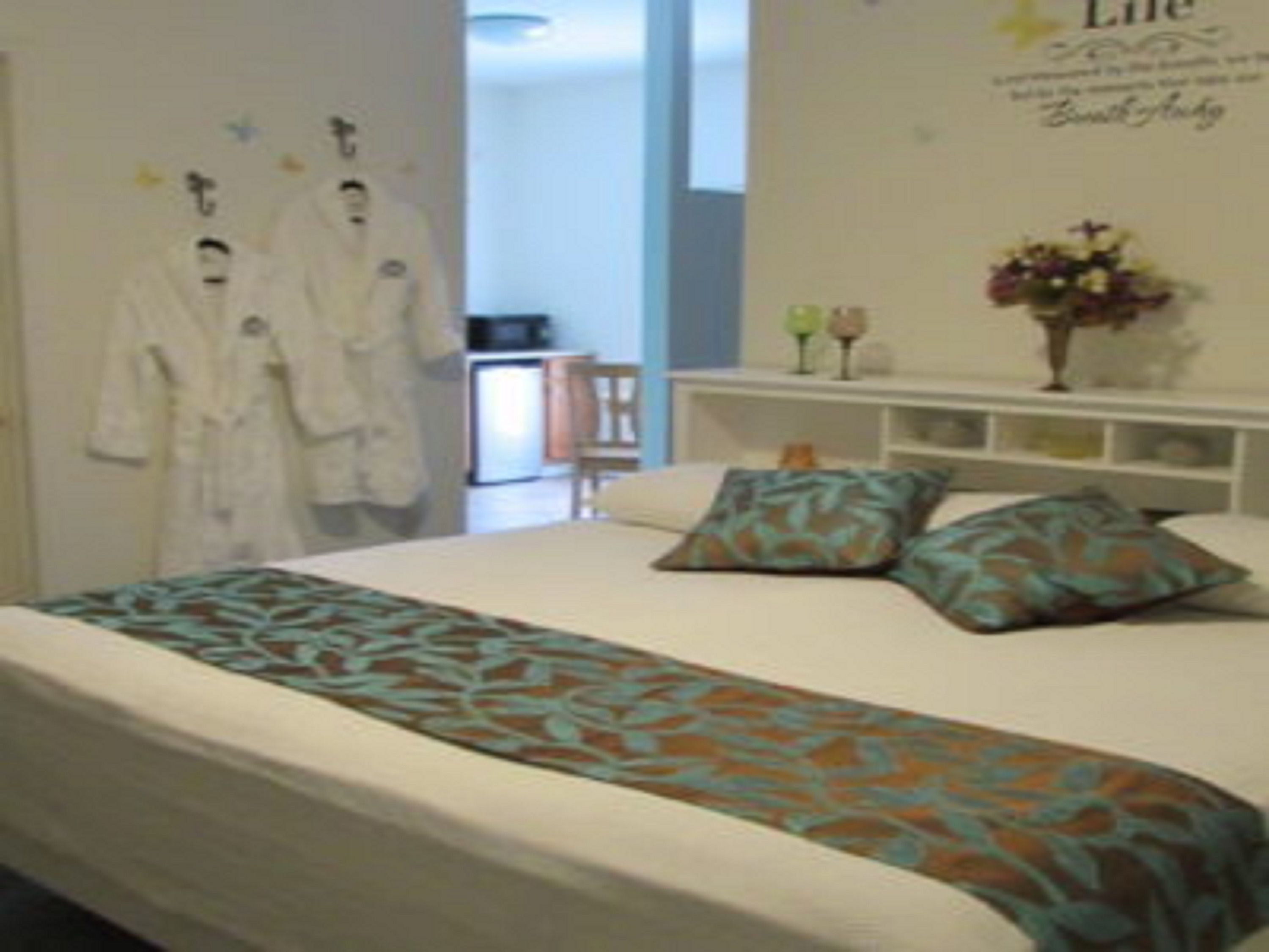 Une chambre d’hôtel avec un lit, des oreillers, une table de chevet et un mur orné d’un panneau décoratif.