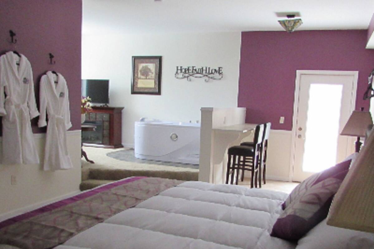 Une chambre à coucher avec un lit, une chaise, un bureau et une baignoire.