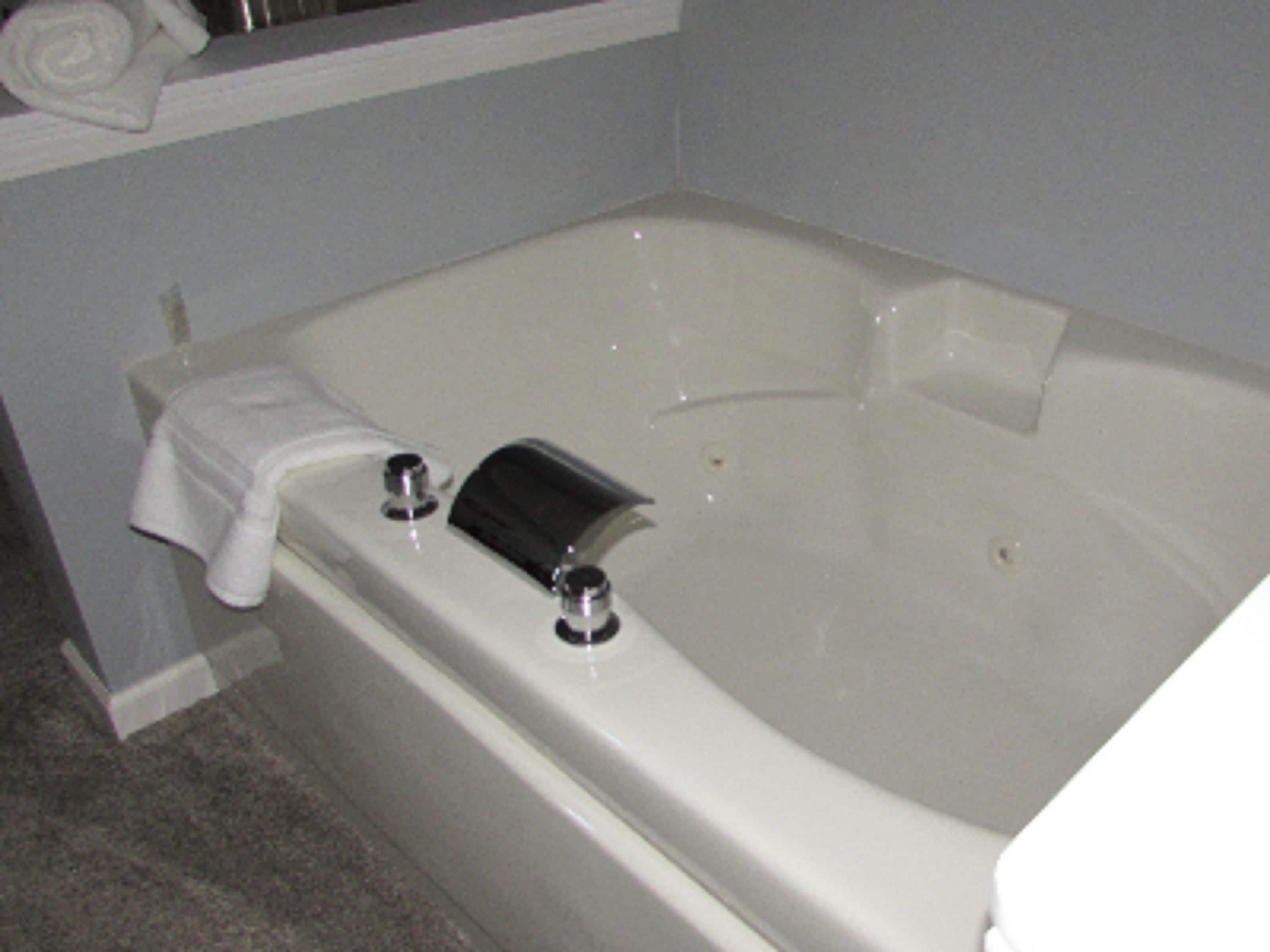 A bathroom with a white bathtub, a towel on the side, and a shower curtain rod.